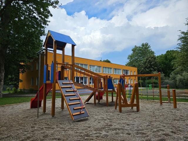 Hřiště s budovou školky v pozadí